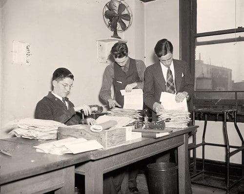 Vintage men sorting papers at table.