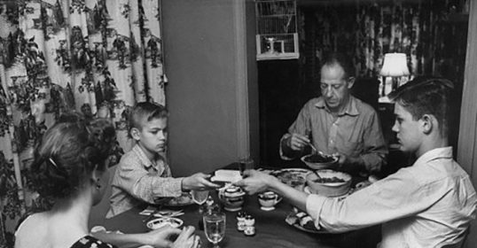 A black and white photo of a family enjoying a dinner together.