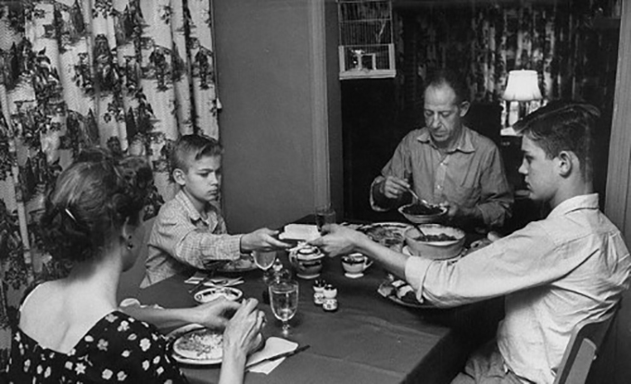 A black and white photo of a family enjoying a dinner together.