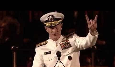 A man in a navy uniform showing peace.