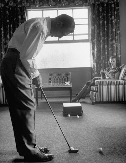 Vintage man playing golf in living room.