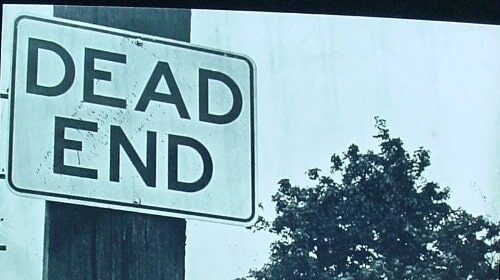 A dead end sign on a pole warns drivers of the abrupt stop ahead.