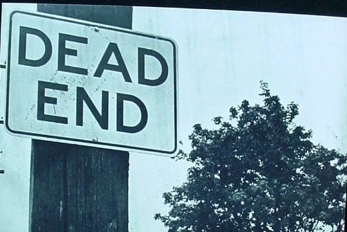 A dead end sign on a pole warns drivers of the abrupt stop ahead.