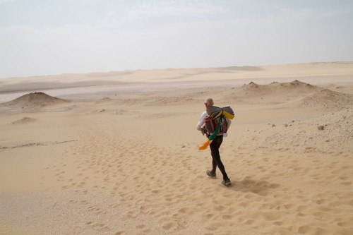 Desert ultramarathon man running in sand.