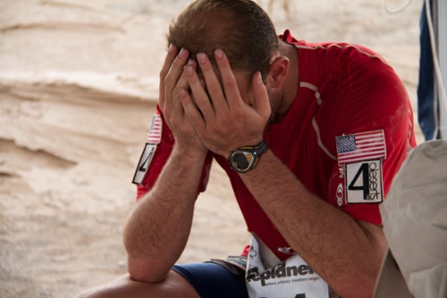 Runner with hands in face exhausted desert ultramarathon.