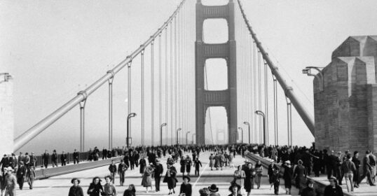 A good day for a black and white photo of people walking across the Golden Gate Bridge.