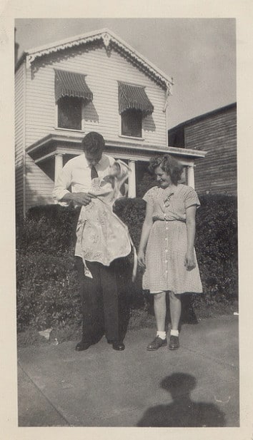 Vintage man holding apron with woman on sidewalk.
