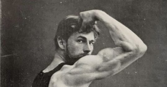 An old photo of a man showcasing his physical vigor by flexing his muscles.