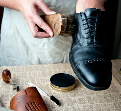 Man brushing polishing black dress shoe close up photo.