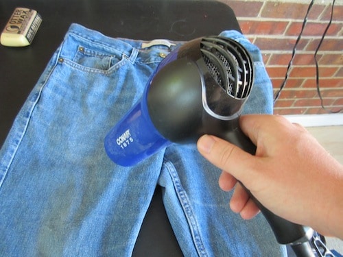 Man using heat dryer on denim jeans.