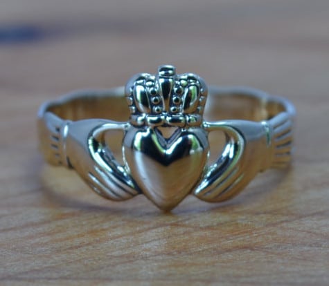 Gold Claddagh engagement ring placed on table.