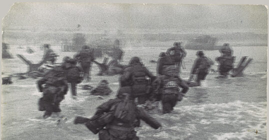 A group of soldiers wading through the water on D-Day, a powerful remembrance of their bravery.