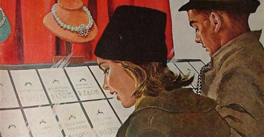 A woman and a man are looking at hats on a magazine cover.