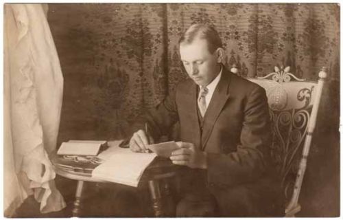 Vintage Victorian man writing letter at table.