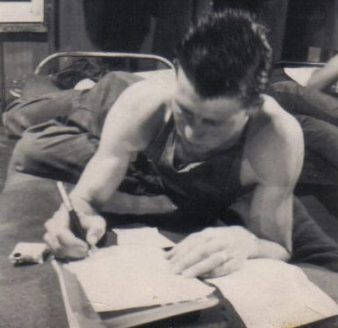 Vintage soldier in cot writing letter.