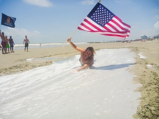 man sliding on beach with american flag adult slip n slide 