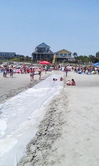 Adult sized mega slip n slide on beach.