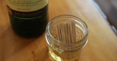 A bottle of whiskey next to a jar of toothpicks for DIY cocktail garnishes.
