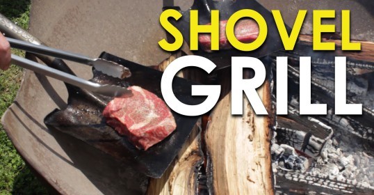 Using a shovel grill, the person is cooking a steak.