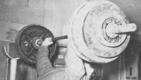 A man is working out with a barbell in the gym.