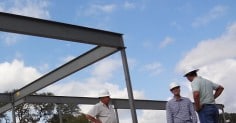 Three architects standing in front of a steel structure.