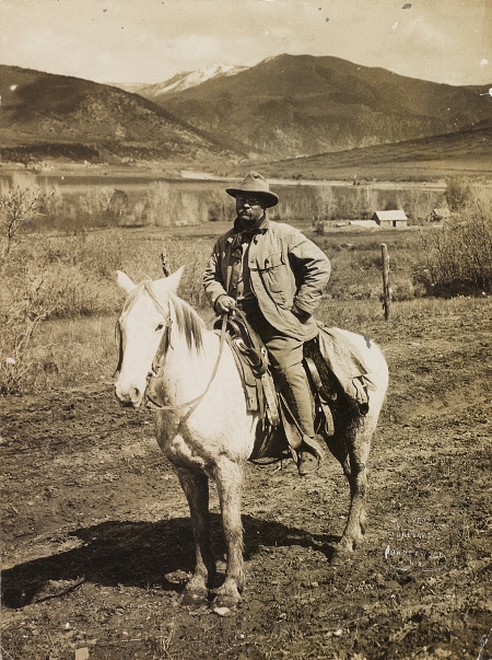 Teddy Theodore riding on horse in mountains. 
