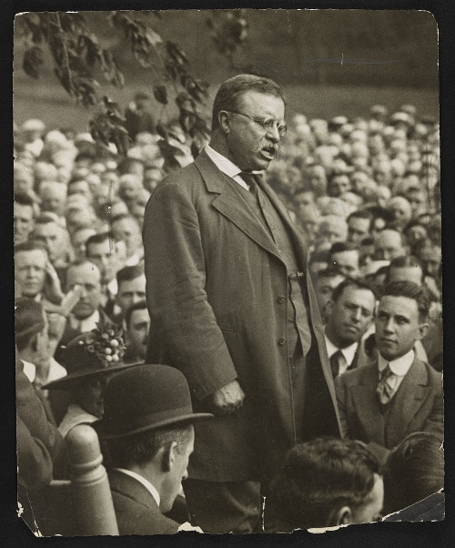 Teddy Theodore standing in public speech.