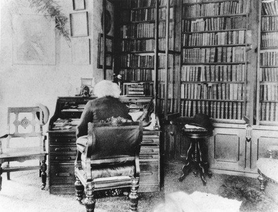 Frederick Douglass sitting on chair in library. 