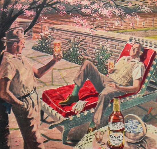 A man is chilling in a lounge chair, sipping on a bottle of whisky.