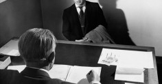 A man in a suit sitting at a desk for an important job interview.