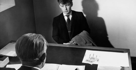 A man in a suit sitting at a desk for an important job interview.