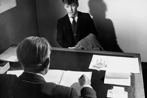 A man in a suit sitting at a desk for an important job interview.