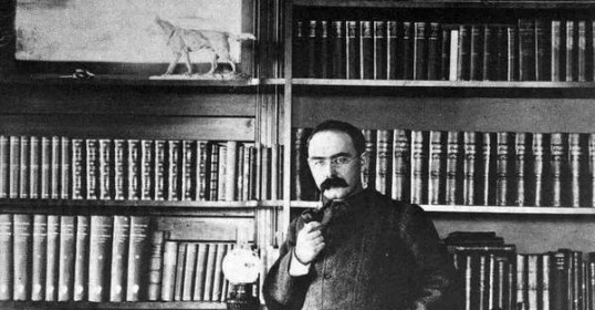 A man in a suit standing in front of a bookshelf from the Gentleman's Guide to Collecting Books.