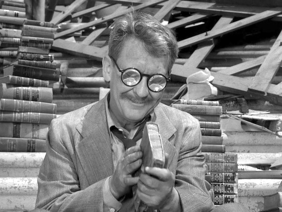 Henry Bemis holding a book in library.