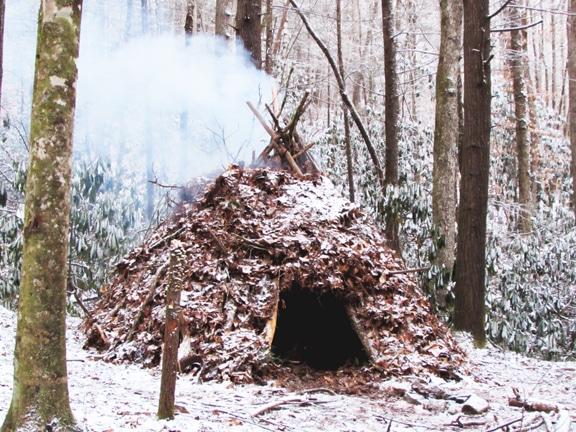 Shelter covering with an internal fire in forest.