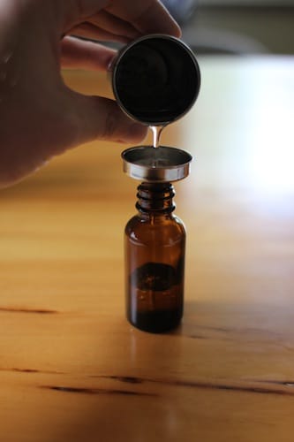 Beard oil pouring into small bottle. 