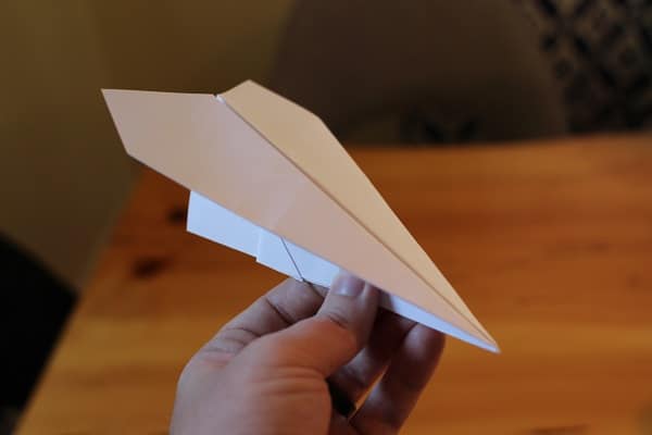 Man holding finished harrier paper airplane.