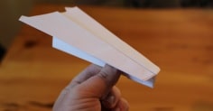 A person showcasing the best paper airplane on a table.