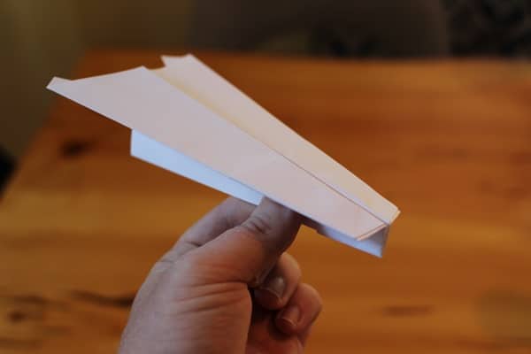 A person showcasing the best paper airplane on a table.