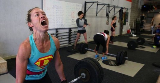 A woman lifting a barbell in a crossfit gym while embracing the Art of Manliness.