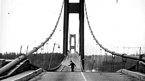 An old black and white photo of a man skateboarding across a bridge, showcasing his skills.