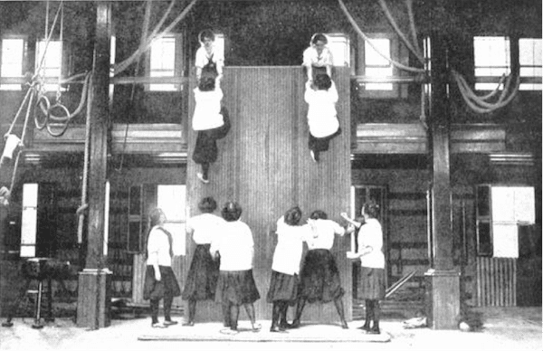 Women climbing a wall in gym gymnasium. 