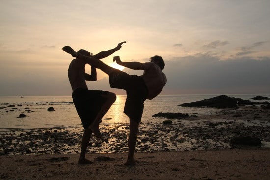 Two men training on beach at sunrise.