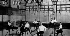 A group of men in a gymnastics room, showcasing their physical fitness.