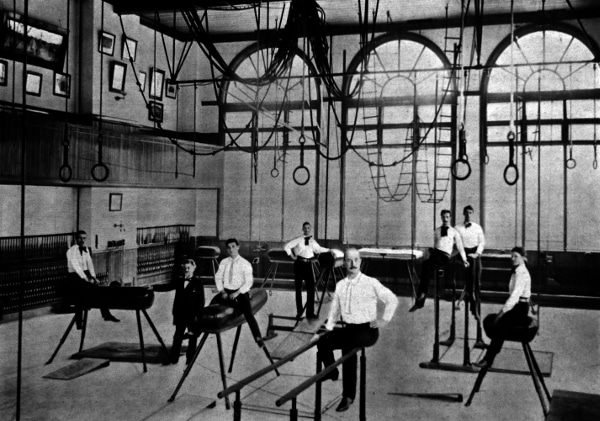 A group of men in a gymnastics room, showcasing their physical fitness.