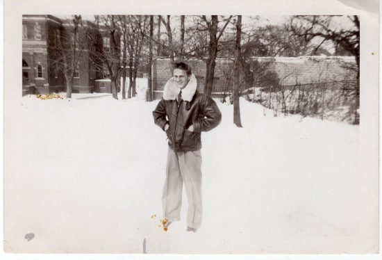 Vintage man wearing leather jacket with fur collar outside in snow. 
