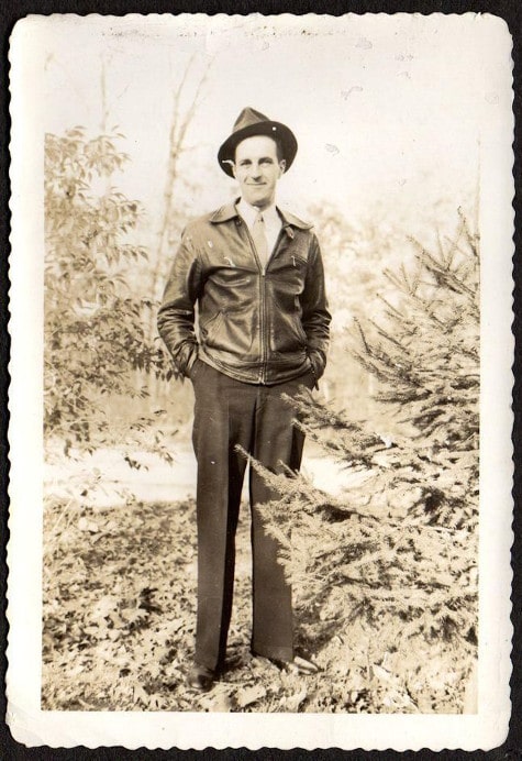 Vintage man posing for picture wearing leather jacket in woods. 