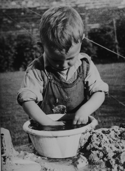Vintage little boy with hands in mud. 