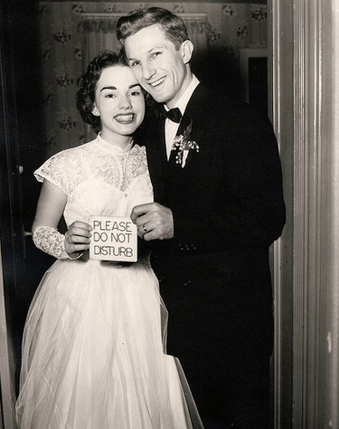 Vintage couple on wedding day holding "please do not disturb" card. 