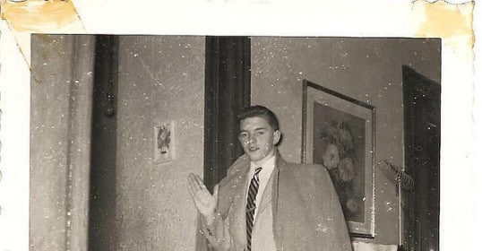 A man in a suit, symbolizing the World Needs Adults, stands confidently in front of a door.